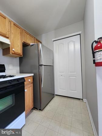 337 Nicholas Dr, Riverside, NJ 08075 - kitchen featuring white gas range oven, light countertops, freestanding refrigerator, under cabinet range hood, and brown cabinets