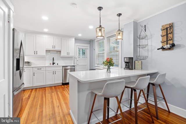 1123 Maple St, Conshohocken, PA 19428 - kitchen with appliances with stainless steel finishes, a peninsula, crown molding, white cabinetry, and a kitchen bar