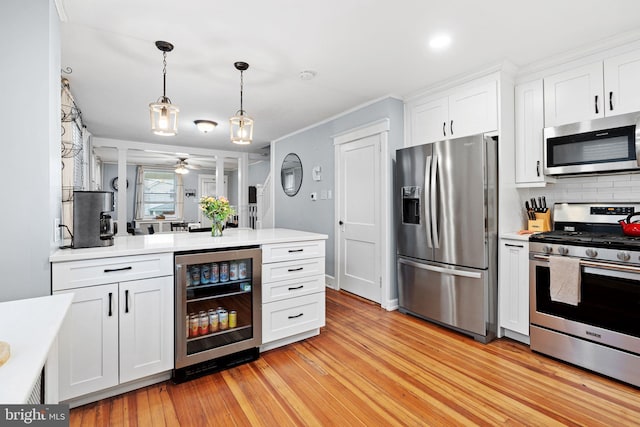 1123 Maple St, Conshohocken, PA 19428 - kitchen featuring appliances with stainless steel finishes, wine cooler, light countertops, white cabinets, and light wood-style flooring