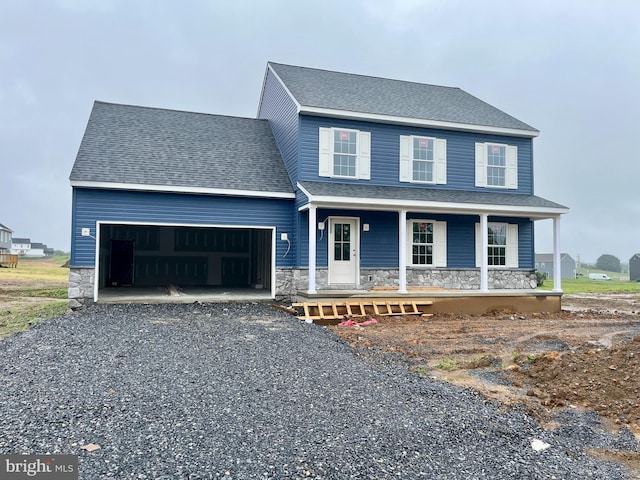 21 American Ave, Carlisle, PA 17013 - view of front of property featuring stone siding, an attached garage, covered porch, driveway, and a shingled roof