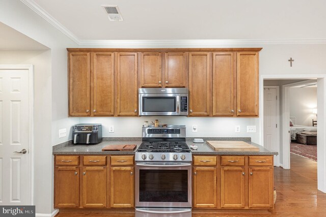 1404 Preserve Ln, Fredericksburg, VA 22401 - kitchen featuring stainless steel appliances, crown molding, wood finished floors, brown cabinetry, and dark countertops