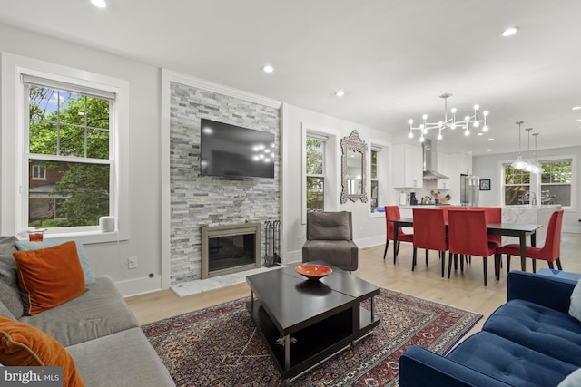 2819 Bellevue Ter NW, Washington, DC 20007 - living room featuring light wood-style flooring, a stone fireplace, a chandelier, and recessed lighting