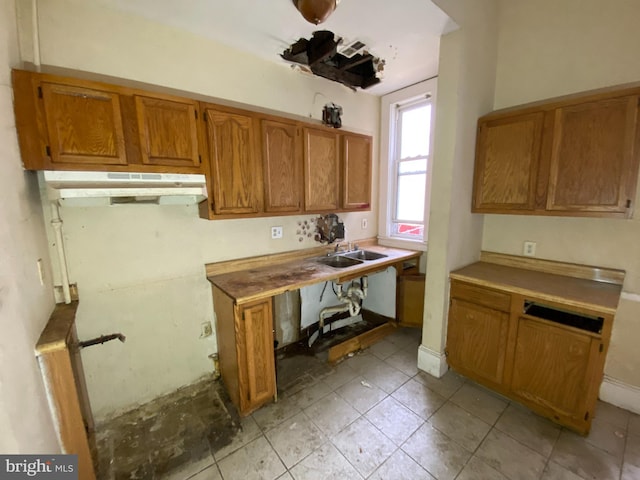 2110 N Charles St N, Baltimore, MD 21218 - kitchen featuring under cabinet range hood, brown cabinets, light tile patterned flooring, and light countertops