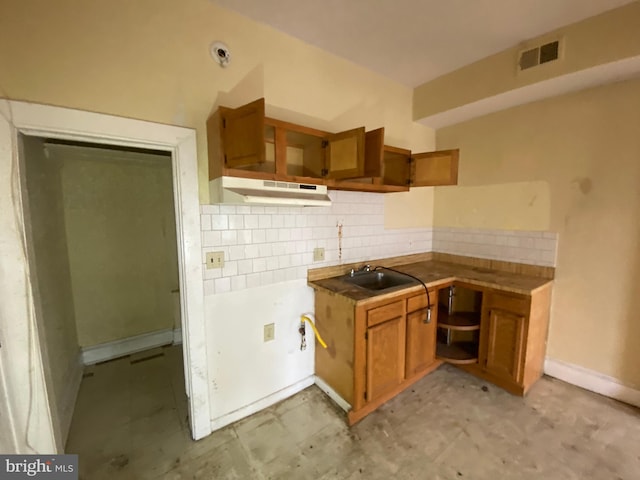 2110 N Charles St N, Baltimore, MD 21218 - kitchen featuring brown cabinets, decorative backsplash, and under cabinet range hood