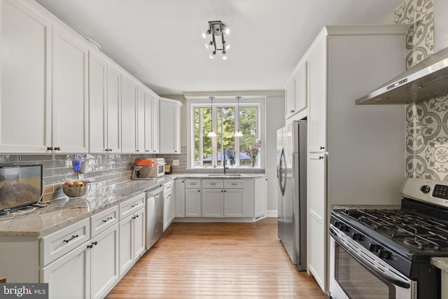 33 Waverly Rd, Wyncote, PA 19095 - kitchen featuring stainless steel appliances, wall chimney range hood, light wood-style flooring, white cabinetry, and tasteful backsplash