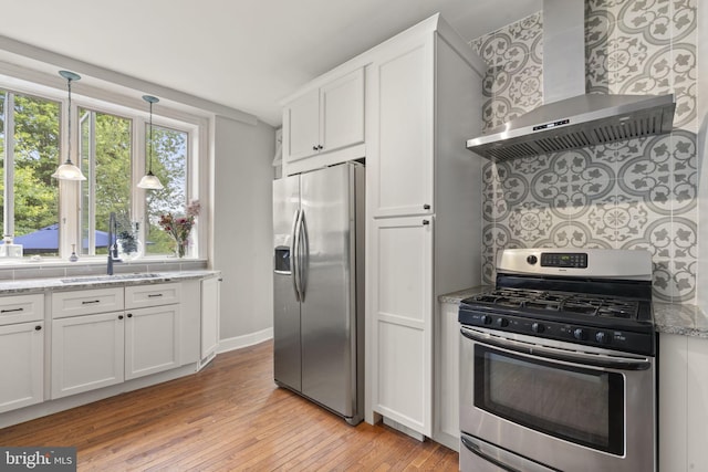 33 Waverly Rd, Wyncote, PA 19095 - kitchen with appliances with stainless steel finishes, wall chimney range hood, light wood-type flooring, white cabinetry, and light stone counters