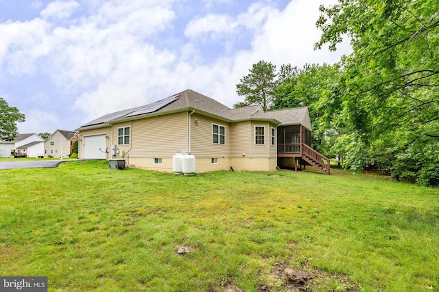 4049 Chatham Dr, King George, VA 22485 - back of house featuring a sunroom, an attached garage, roof mounted solar panels, and a lawn