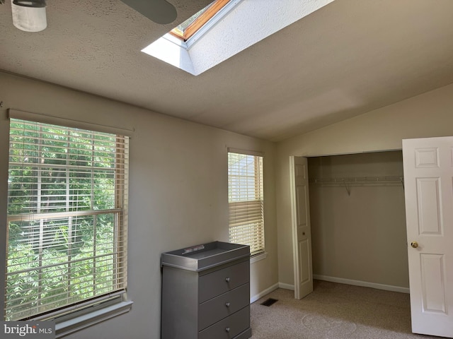 8902 Chesapeake Lighthouse Dr, North Beach, MD 20714 - bedroom featuring a skylight, light carpet, vaulted ceiling, a closet, and a textured ceiling