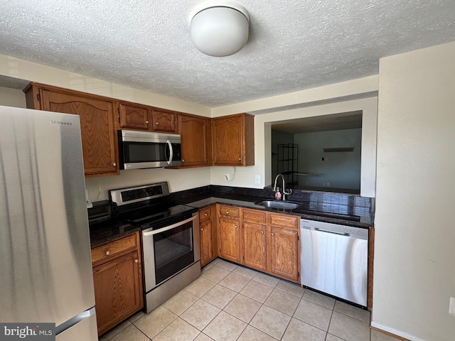 8902 Chesapeake Lighthouse Dr, North Beach, MD 20714 - kitchen with appliances with stainless steel finishes, dark countertops, light tile patterned floors, brown cabinetry, and a textured ceiling