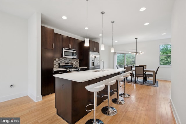 914 N Front St, Philadelphia, PA 19123 - kitchen with stainless steel appliances, a breakfast bar, a kitchen island with sink, dark brown cabinets, and light countertops