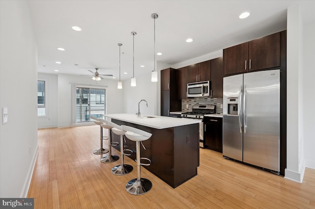914 N Front St, Philadelphia, PA 19123 - kitchen featuring stainless steel appliances, a breakfast bar, light countertops, an island with sink, and dark brown cabinets