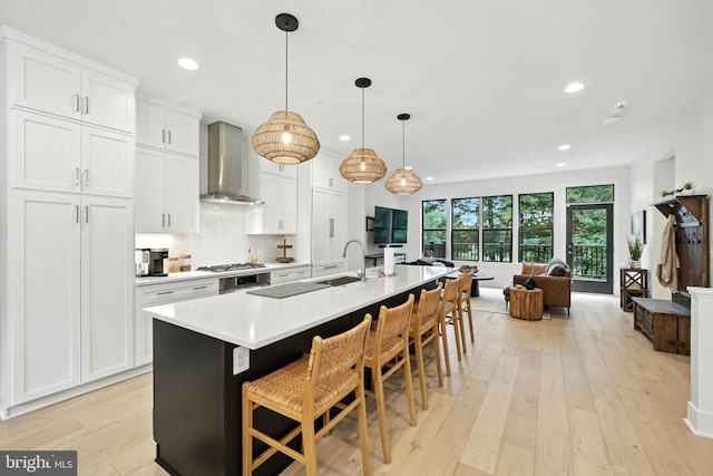 3536 Sutton Heights Cir, Fairfax, VA 22031 - kitchen with wall chimney exhaust hood, white cabinetry, light wood-style flooring, an island with sink, and light countertops