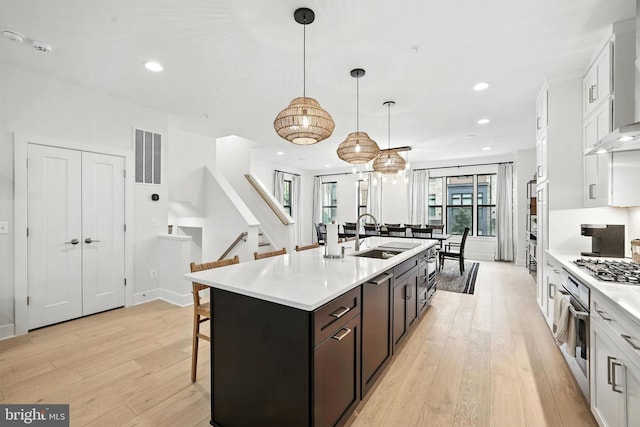 3536 Sutton Heights Cir, Fairfax, VA 22031 - kitchen featuring a breakfast bar, light wood-style floors, light countertops, white cabinetry, and wall chimney exhaust hood