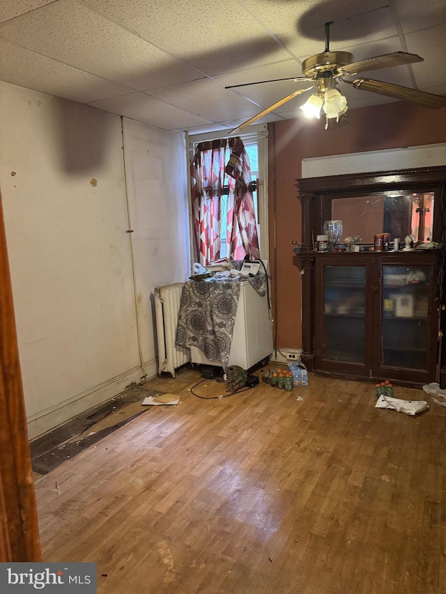 2008 W Lexington St, Baltimore, MD 21223 - unfurnished living room featuring radiator, wood finished floors, and a ceiling fan