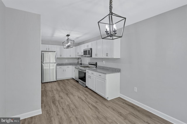 18721 Paprika Ct, Germantown, MD 20874 - kitchen featuring appliances with stainless steel finishes, a chandelier, white cabinets, and light wood-style flooring