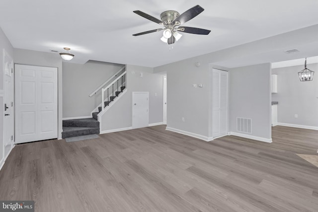 18721 Paprika Ct, Germantown, MD 20874 - unfurnished living room featuring wood finished floors, stairs, a ceiling fan, and a chandelier