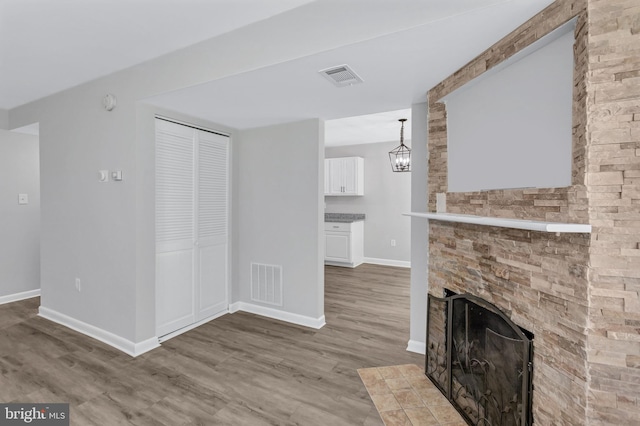 18721 Paprika Ct, Germantown, MD 20874 - unfurnished living room featuring wood finished floors, a fireplace, and a chandelier