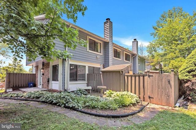 18721 Paprika Ct, Germantown, MD 20874 - rear view of house featuring a chimney, a gate, and brick siding