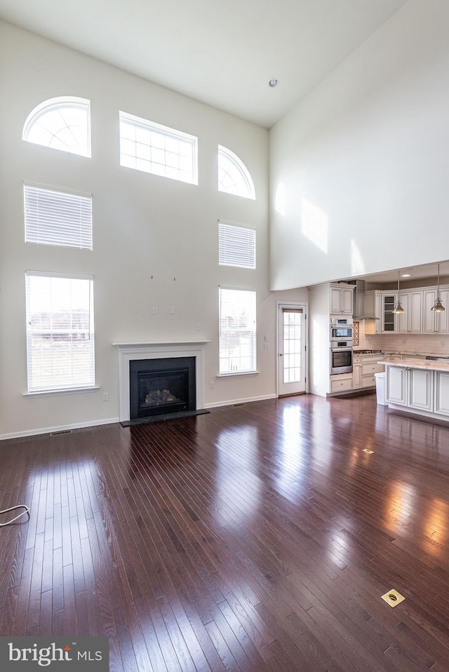 4251 Beech Dr, Nazareth, PA 18064 - unfurnished living room featuring a towering ceiling, a fireplace with flush hearth, and dark wood-type flooring