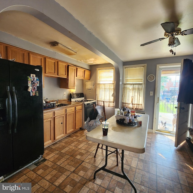 3648 Benson Ave, Baltimore, MD 21227 - kitchen with freestanding refrigerator, white gas range, brick patterned flooring, and arched walkways