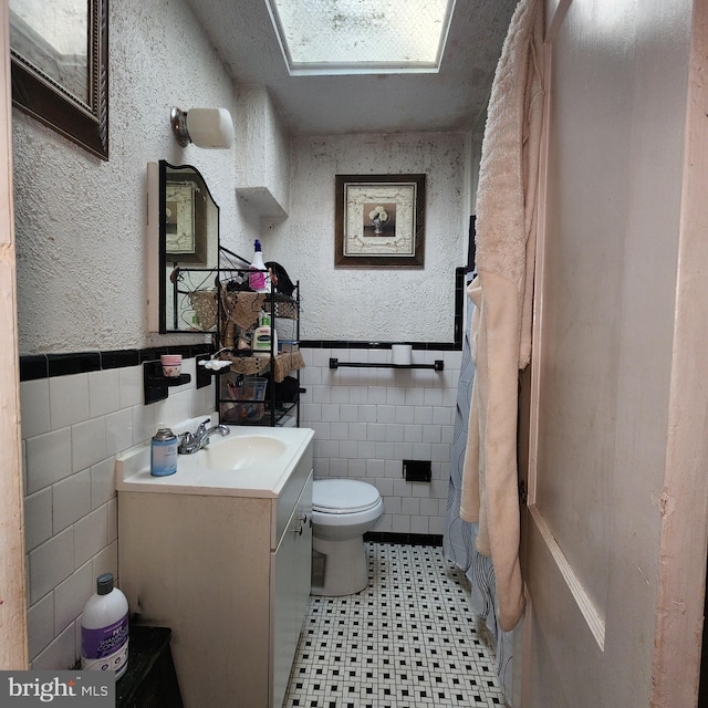 3648 Benson Ave, Baltimore, MD 21227 - bathroom with tile walls, tile patterned floors, vanity, a wainscoted wall, and a textured wall