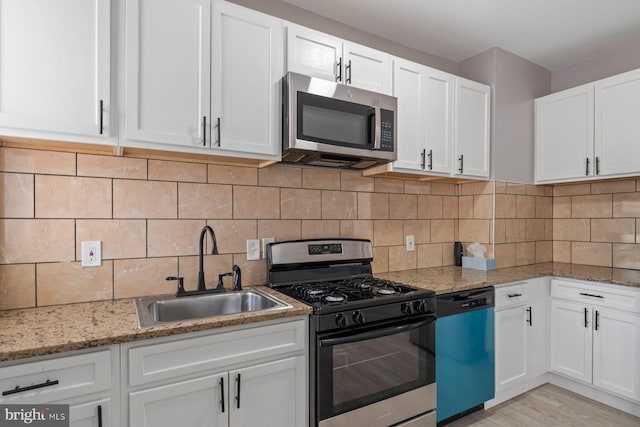 1539 N Payson St, Baltimore, MD 21217 - kitchen featuring stainless steel microwave, gas range, dishwashing machine, white cabinetry, and light stone countertops