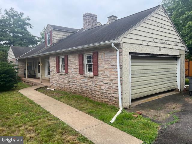 60 Buckwalter Rd, Royersford, PA 19468 - view of side of property featuring stone siding, asphalt driveway, a chimney, a garage, and covered porch