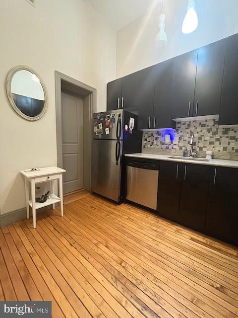511 S Bond St Unit 304, Baltimore, MD 21231 - kitchen with dark cabinets, stainless steel dishwasher, freestanding refrigerator, light countertops, and a towering ceiling