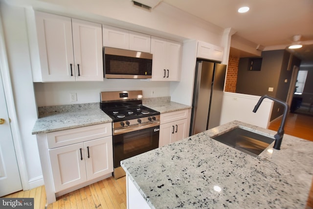 2902 Hudson St, Baltimore, MD 21224 - kitchen featuring appliances with stainless steel finishes, white cabinetry, light wood-type flooring, light stone countertops, and recessed lighting