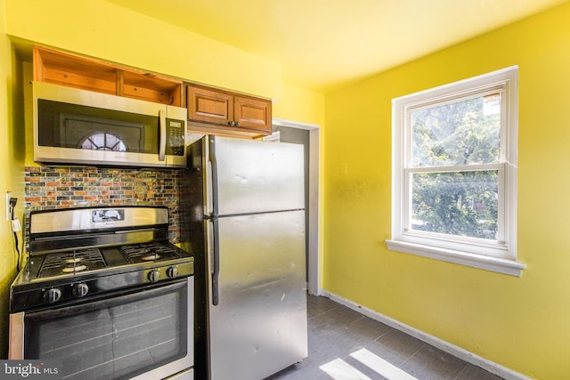 627 Forrester St SE, Washington, DC 20032 - kitchen with black gas stove, stainless steel microwave, freestanding refrigerator, and brown cabinets