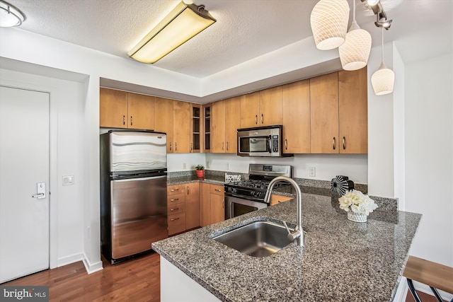 475 K St NW Unit 630, Washington, DC 20001 - kitchen featuring stainless steel appliances, a peninsula, dark stone countertops, dark wood-style floors, and brown cabinetry