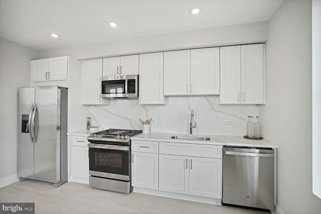 901 19th St NE Unit Ph2, Washington, DC 20002 - kitchen featuring appliances with stainless steel finishes, decorative backsplash, white cabinetry, light wood-style flooring, and recessed lighting