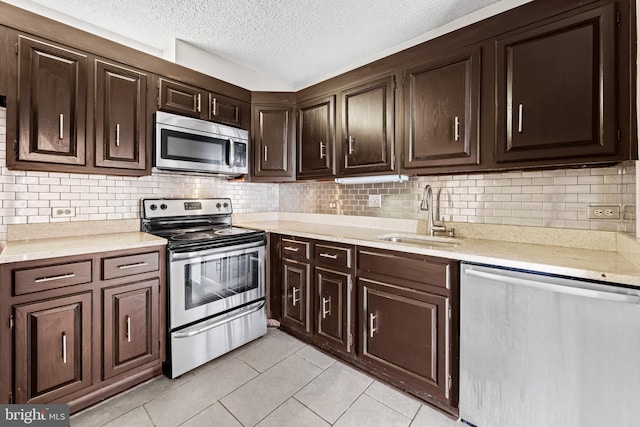 4100 N Charles St N Unit 803, Baltimore, MD 21218 - kitchen featuring appliances with stainless steel finishes, light tile patterned floors, dark brown cabinetry, a textured ceiling, and decorative backsplash