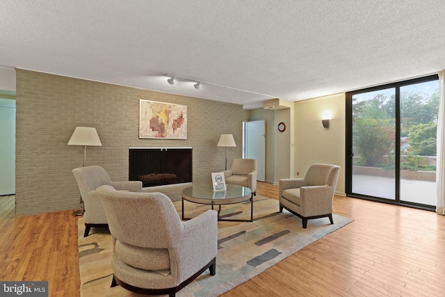 4100 N Charles St N Unit 803, Baltimore, MD 21218 - living area with wood finished floors, a textured ceiling, a fireplace, a wall of windows, and brick wall