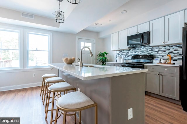 1616 C St NE, Washington, DC 20002 - kitchen featuring black appliances, a kitchen breakfast bar, wood finished floors, backsplash, and a center island with sink