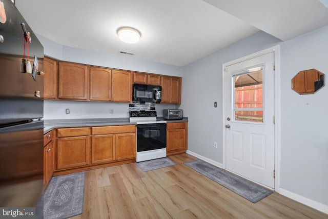 14361 Springbrook Ct, Woodbridge, VA 22193 - kitchen with electric stove, freestanding refrigerator, light wood-style flooring, black microwave, and brown cabinets