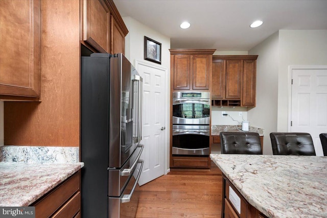 35 Gallery Rd, Stafford, VA 22554 - kitchen featuring appliances with stainless steel finishes, light wood-style floors, brown cabinetry, light stone counters, and recessed lighting