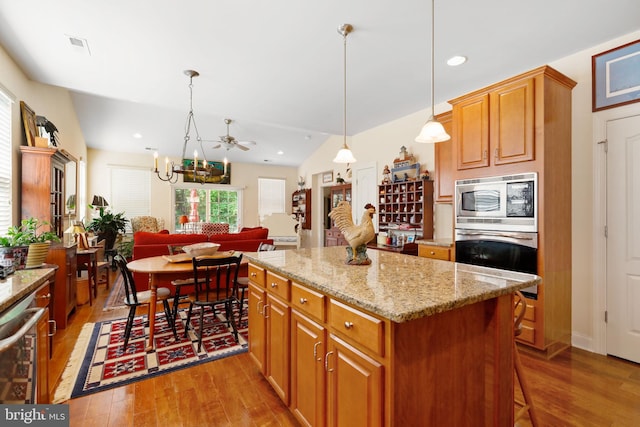 13 Doddington Blvd, Medford, NJ 08055 - kitchen with stainless steel appliances, wood finished floors, a kitchen island, light stone counters, and brown cabinetry