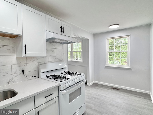 1504 Bonwood Rd, Wilmington, DE 19805 - kitchen featuring white gas range oven, under cabinet range hood, healthy amount of natural light, and white cabinetry