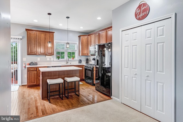 107 Pelican Cv, Stafford, VA 22554 - kitchen with black appliances, a center island, brown cabinets, a breakfast bar, and light countertops