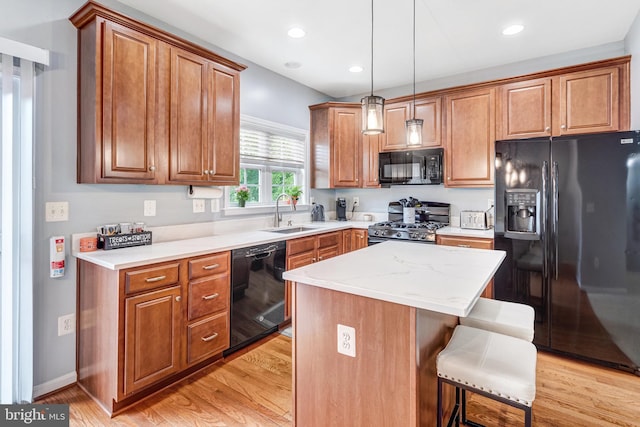 107 Pelican Cv, Stafford, VA 22554 - kitchen featuring black appliances, light wood-type flooring, a breakfast bar, brown cabinetry, and a center island