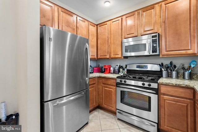 12000 Market St Unit 378, Reston, VA 20190 - kitchen with stainless steel appliances, light tile patterned flooring, light stone countertops, and brown cabinets