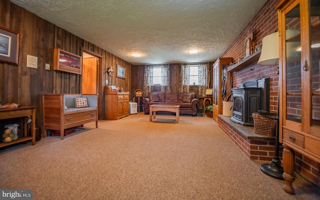 1 Emerald St, Mill Hall, PA 17751 - living area featuring carpet flooring, a wood stove, wood walls, and a textured ceiling