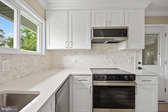 116 Hollow Rd, Levittown, PA 19056 - kitchen featuring stainless steel appliances, light countertops, decorative backsplash, white cabinets, and ornamental molding