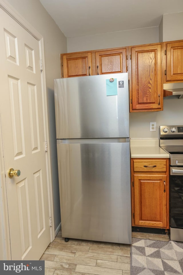 11 Bryce Ct, Baltimore, MD 21236 - kitchen with stainless steel appliances, light wood-style flooring, brown cabinetry, light countertops, and under cabinet range hood