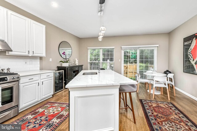 1246 Vintage Pl, Reston, VA 20194 - kitchen with wine cooler, stainless steel range, light wood-type flooring, a kitchen bar, and white cabinetry