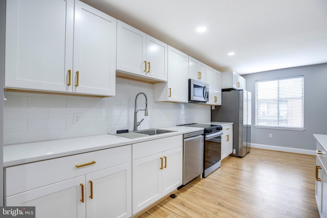 9704 Kingsbridge Dr Unit 203, Fairfax, VA 22031 - kitchen featuring stainless steel appliances, tasteful backsplash, light countertops, light wood-style floors, and white cabinets