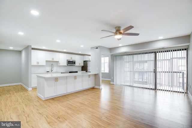 9704 Kingsbridge Dr Unit 203, Fairfax, VA 22031 - kitchen with stainless steel appliances, light countertops, ceiling fan, white cabinetry, and light wood-style flooring