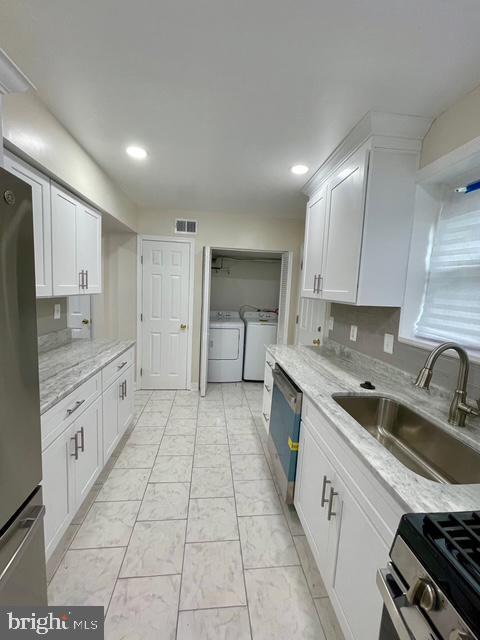 2301 Wyngate Rd, Suitland, MD 20746 - kitchen with separate washer and dryer, stainless steel appliances, white cabinetry, recessed lighting, and light stone counters