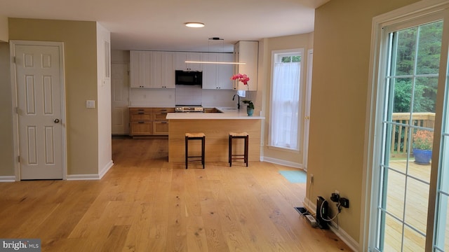 112 Pine Crest Ln, Gordonsville, VA 22942 - kitchen featuring black microwave, a breakfast bar, light wood-style floors, a peninsula, and light countertops